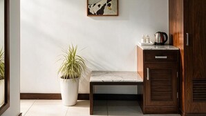 A room with a bench, a potted plant, a cabinet, and a wall-mounted artwork. - Hotel Oasis One (Gurugram)