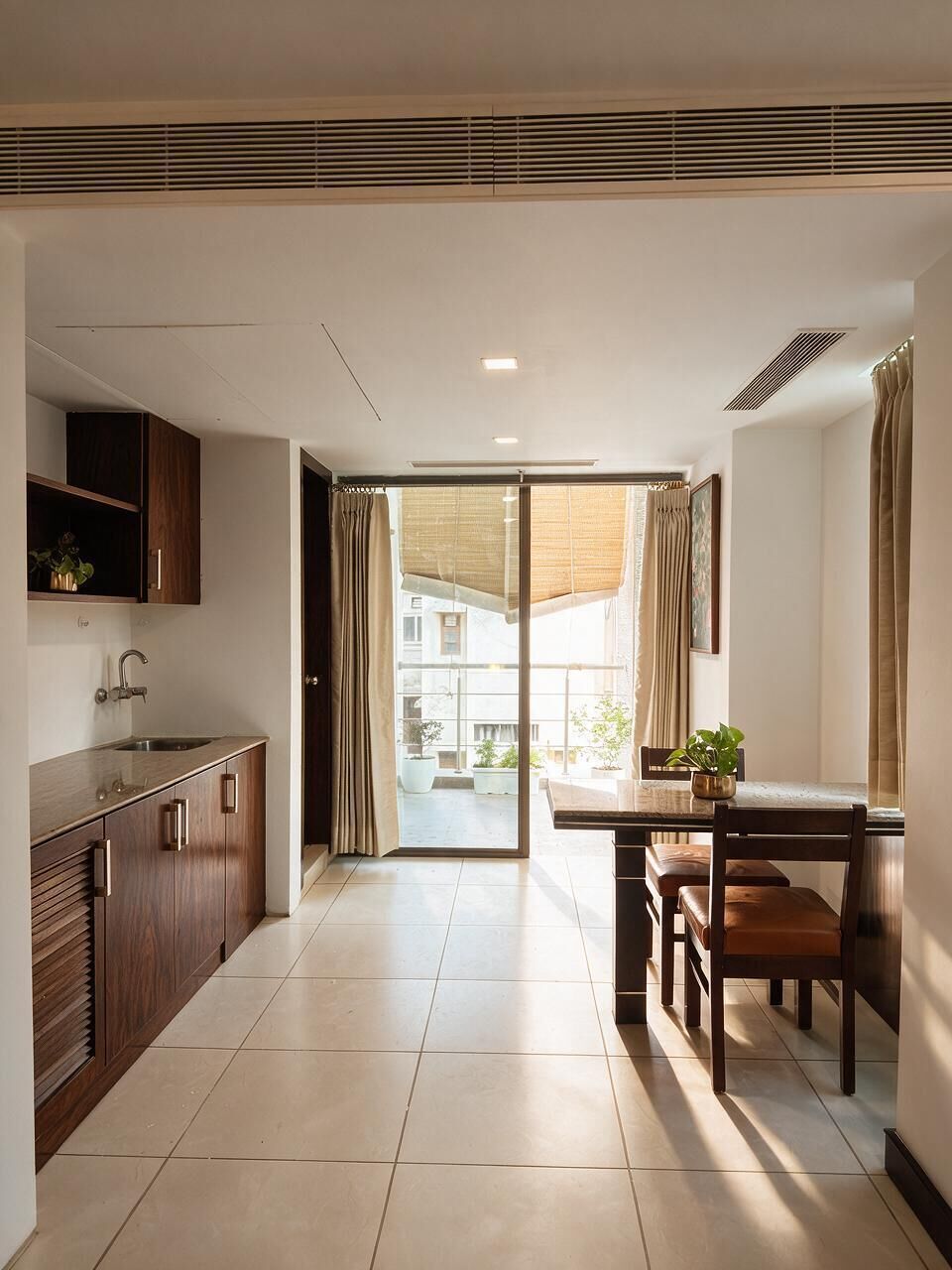 A modern kitchen with a built-in sink, wooden cabinets, and a dining area with a table and chairs.
