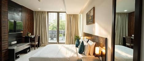 Camera d'albergo con un letto grande, una scrivania, un televisore e un balcone con tende.