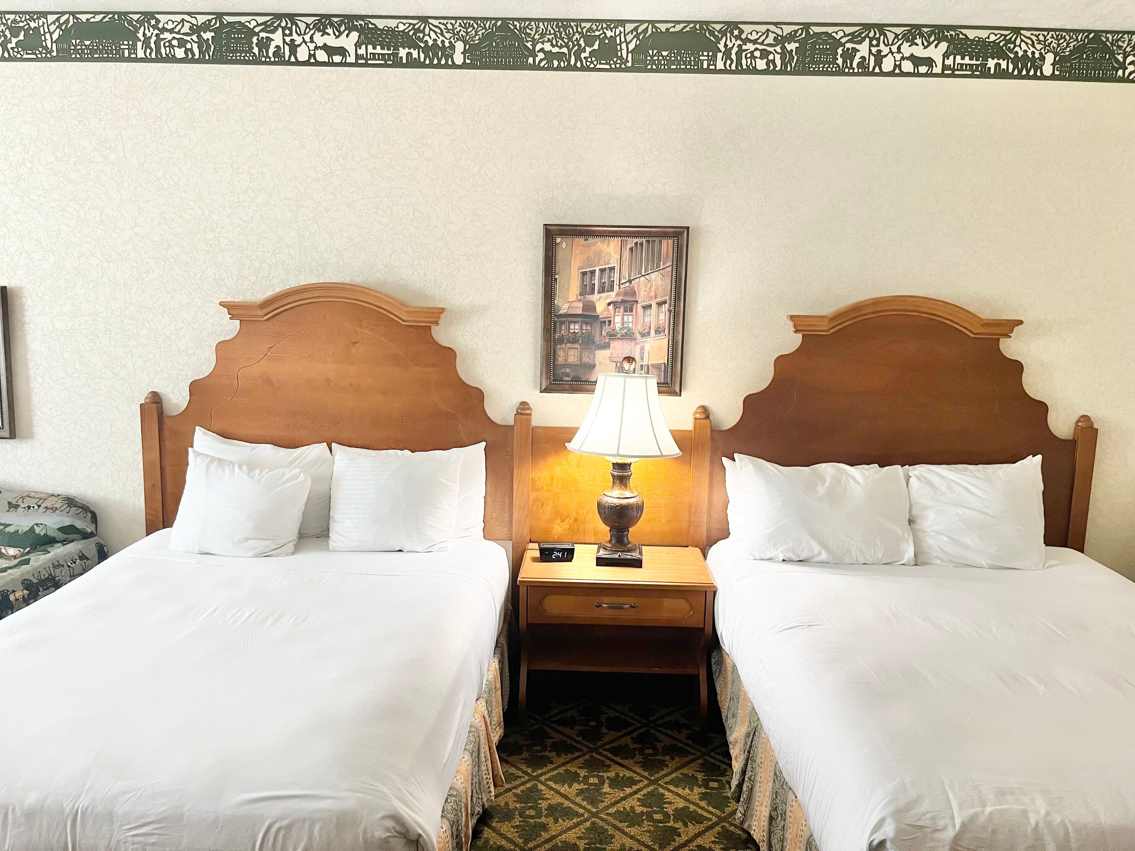 Ein Hotelzimmer mit zwei Einzelbetten, einem Nachttisch mit Lampe und einem gerahmten Bild an der Wand.