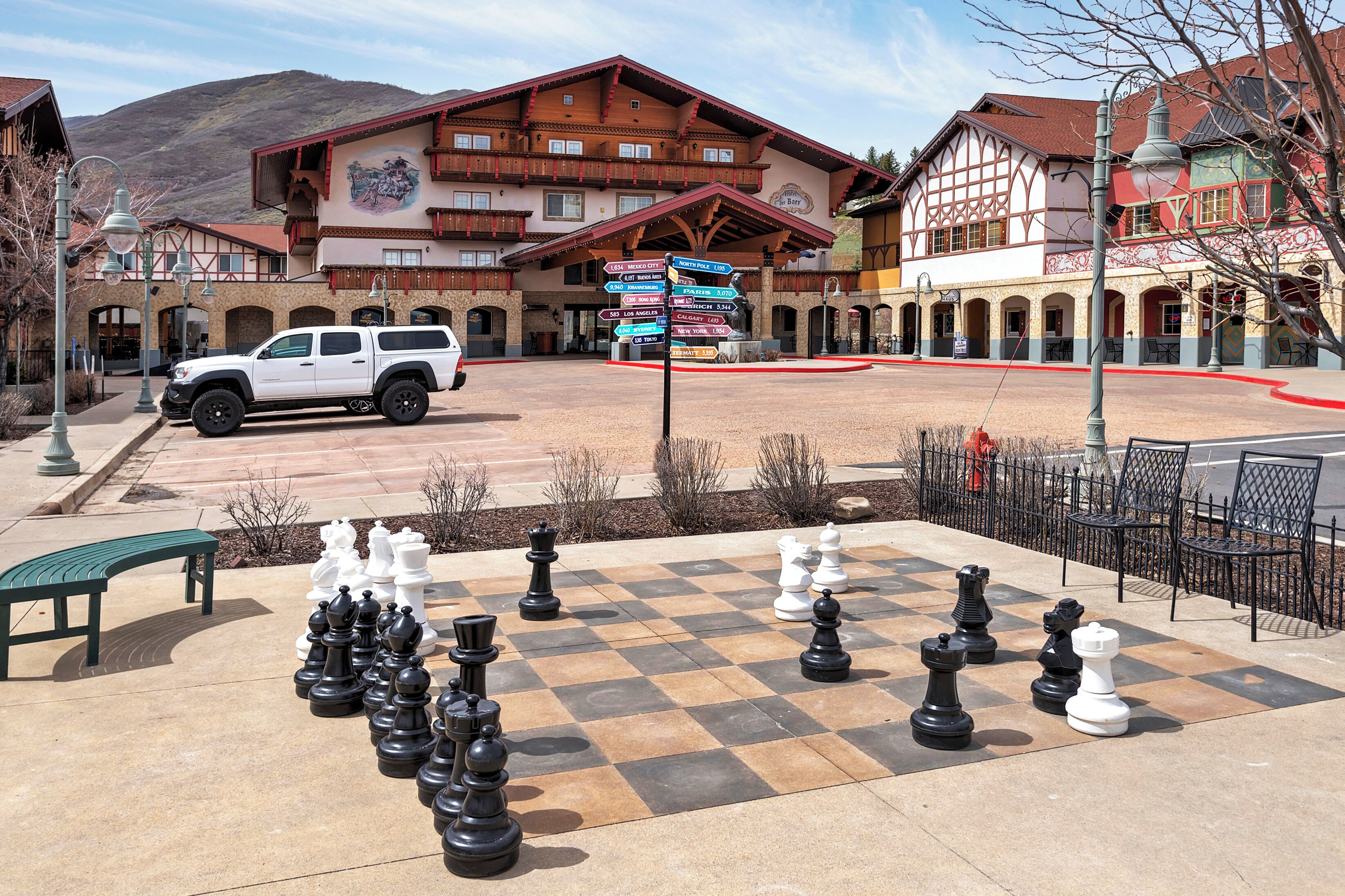 A large outdoor chessboard with a white SUV parked nearby.