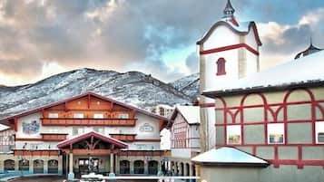 A traditional building with a red and white facade, a bell tower, and a mountainous backdrop.