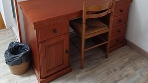 A wooden desk with drawers and a chair in a room with a white wall and a framed picture. - E lu chantauziau (La Monnerie-le-Montel)