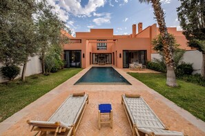 A modern house with a swimming pool, two lounge chairs, and a small table. - Riad Safran Al Maaden Golf – Marrakech (Marrakech)