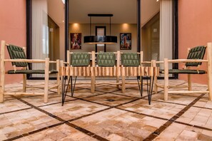 A room with a wooden table and four chairs with woven seats, a tiled floor, and artwork on the walls. - Riad Safran Al Maaden Golf – Marrakech (Marrakech)