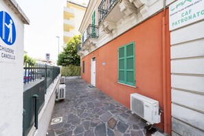 A narrow alley with a stone pavement, a white building with green shutters, and a sign indicating a parking area. - An elegant 62 sqm flat, ideal for three people, located on the ground floor of an Art Nouveau villa.The property enjoys a strategic location just a short distance from Pescara city center.The hospital is within a 5-minute walk, while the seaside is a 5-m (Pescara)