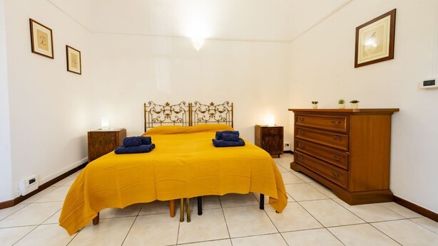 A bedroom with a double bed, wooden headboard, bedside tables, a dresser, and framed pictures on the walls. - An elegant 62 sqm flat, ideal for three people, located on the ground floor of an Art Nouveau villa.The property enjoys a strategic location just a short distance from Pescara city center.The hospital is within a 5-minute walk, while the seaside is a 5-m (Pescara)