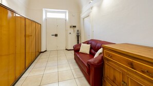 A hallway with a red leather sofa, wooden cabinets, and a white door. - An elegant 62 sqm flat, ideal for three people, located on the ground floor of an Art Nouveau villa.The property enjoys a strategic location just a short distance from Pescara city center.The hospital is within a 5-minute walk, while the seaside is a 5-m (Pescara)
