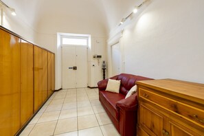 A hallway with a red leather sofa, wooden cabinets, and a white door. - An elegant 62 sqm flat, ideal for three people, located on the ground floor of an Art Nouveau villa.The property enjoys a strategic location just a short distance from Pescara city center.The hospital is within a 5-minute walk, while the seaside is a 5-m (Pescara)