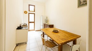 A small, well-lit kitchen with a wooden table, chairs, a sink, and a refrigerator. - An elegant 62 sqm flat, ideal for three people, located on the ground floor of an Art Nouveau villa.The property enjoys a strategic location just a short distance from Pescara city center.The hospital is within a 5-minute walk, while the seaside is a 5-m (Pescara)