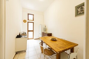 A small, well-lit kitchen with a wooden table, chairs, a sink, and a refrigerator. - An elegant 62 sqm flat, ideal for three people, located on the ground floor of an Art Nouveau villa.The property enjoys a strategic location just a short distance from Pescara city center.The hospital is within a 5-minute walk, while the seaside is a 5-m (Pescara)