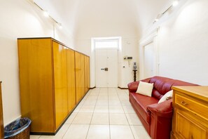 Ein Flur mit einem Holzschrank, einem roten Sofa und einer kleinen Mülltonne.