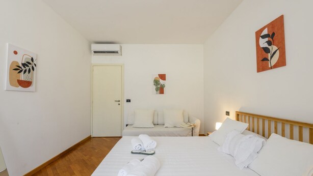 Een hotelkamer met een bed, nachtkastje, stoel en kunstwerken aan de wanden.
