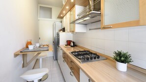 Een moderne keuken met een gasfornuis, houten kastjes en een roestvrijstalen koelkast.