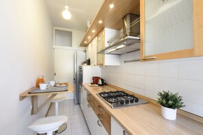 Eine moderne Küche mit einem Gasherd, Holzschränken und einem Edelstahl-Kühlschrank.