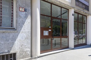 Una entrada de edificio con puerta de cristal, reja de metal y un letrero con números.