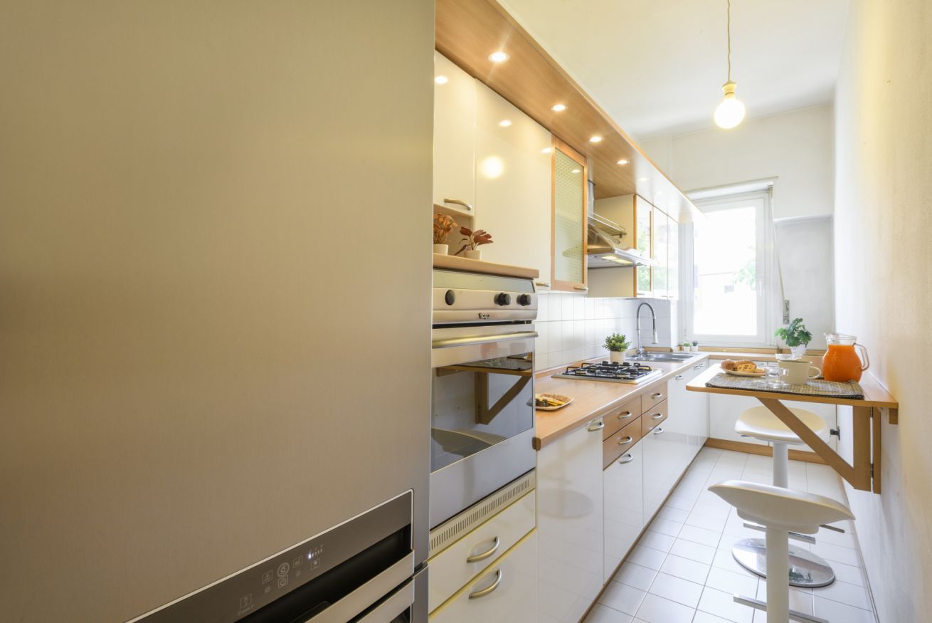 A modern kitchen with built-in appliances, a wooden countertop, and a window providing natural light.