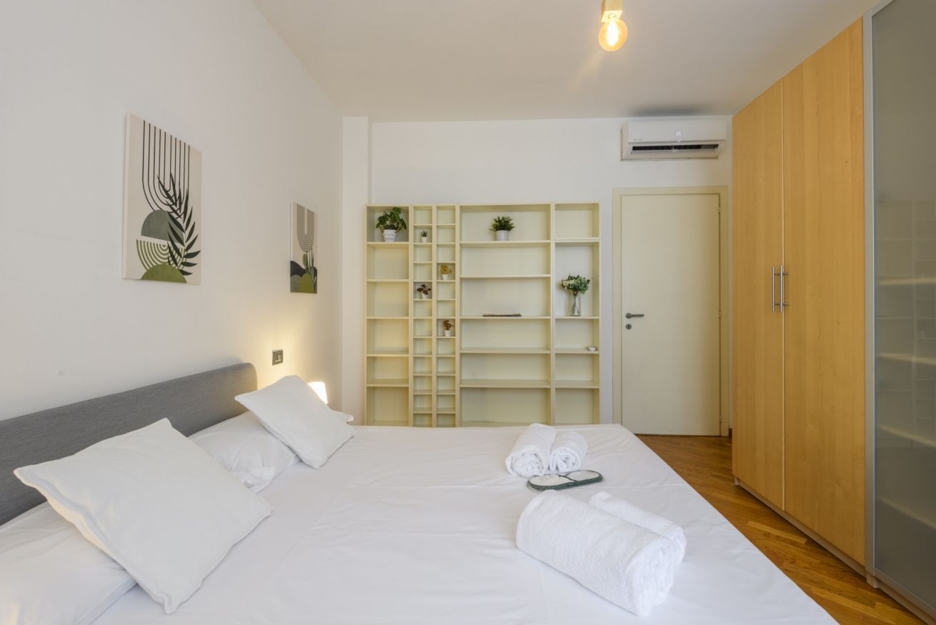 Een hotelkamer met een bed, een kledingkast, een plank met planten en een deur.