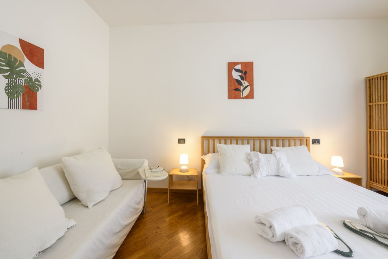 Ein Hotelzimmer mit einem Bett, einer Couch, einem Nachttisch mit Lampe und einem Holz-Kopfteil.