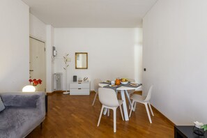 A modern dining area with a round table, white chairs, and a small white cabinet. - Mussi, 10 – Between CityLife and Sempione (Milan)