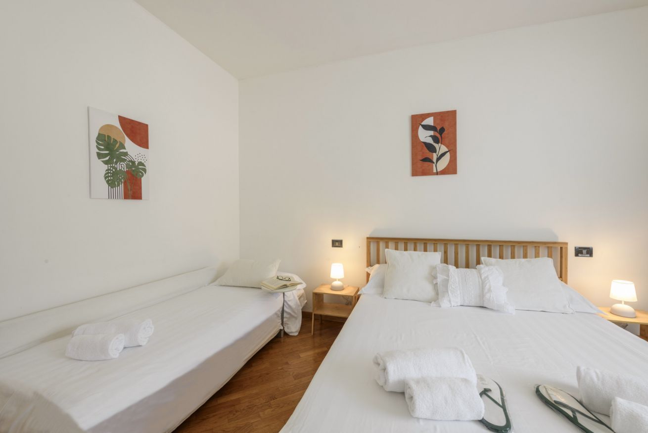 A hotel room with two single beds, a wooden headboard, white bedding, and two wall-mounted paintings.