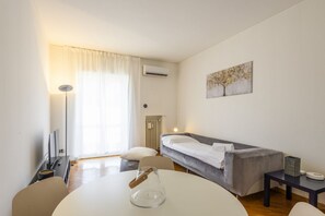 Ein modernes Hotelzimmer mit einem Bett, einem Esstisch, einem Stuhl, einer Lampe und einem Gemälde an der Wand.