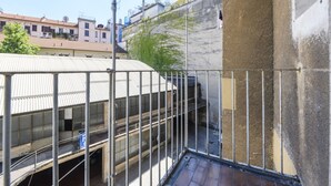 Een balkon met metalen hekwerk, uitkijkend op een gebouw met een pannendak.