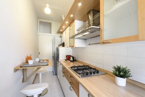 A modern kitchen with a gas stove, wooden cabinets, and a stainless steel refrigerator. - Mussi, 10 – Between CityLife and Sempione (Milan)