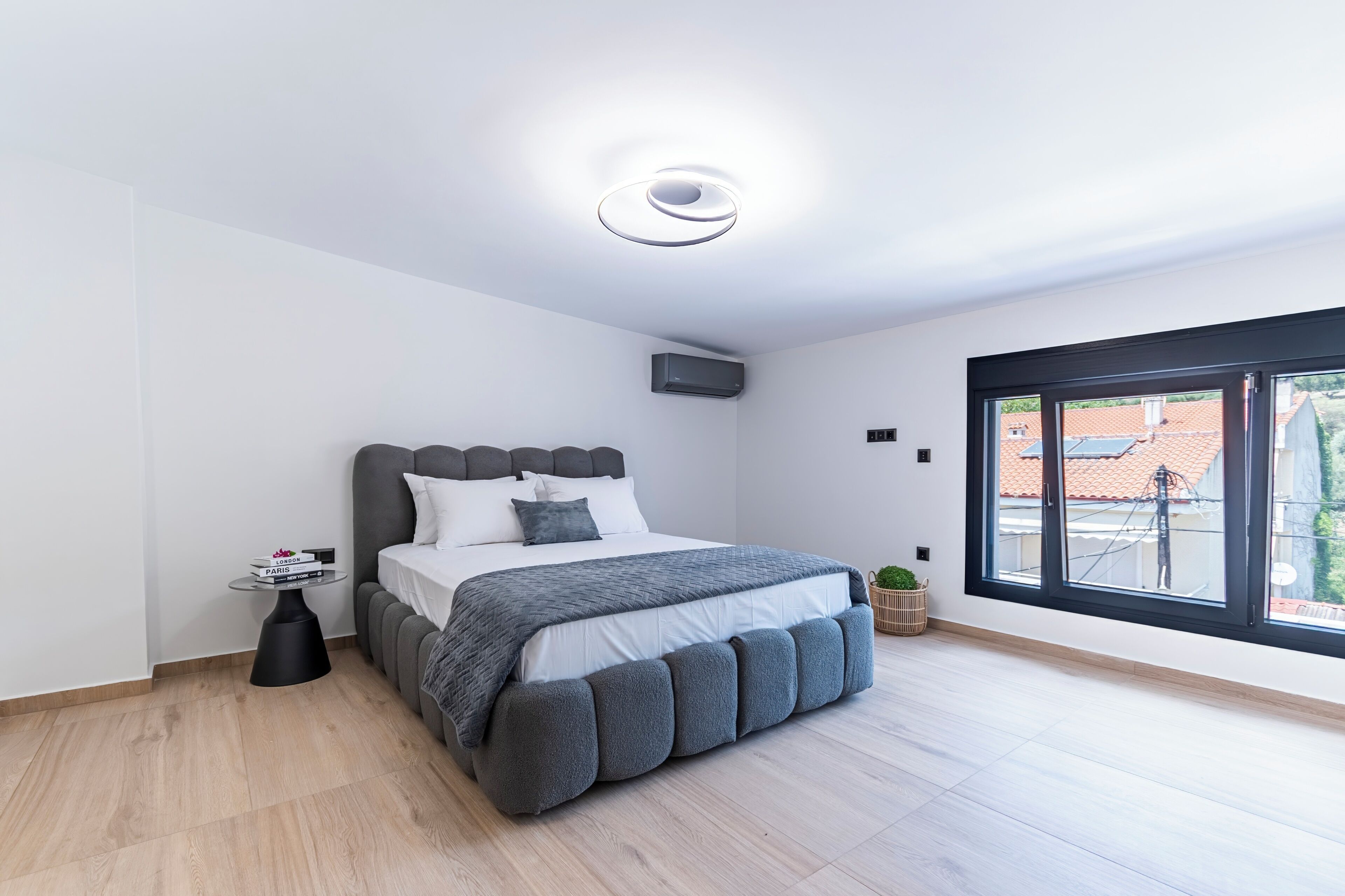 Un dormitorio moderno con cama, mesita de noche y ventana.