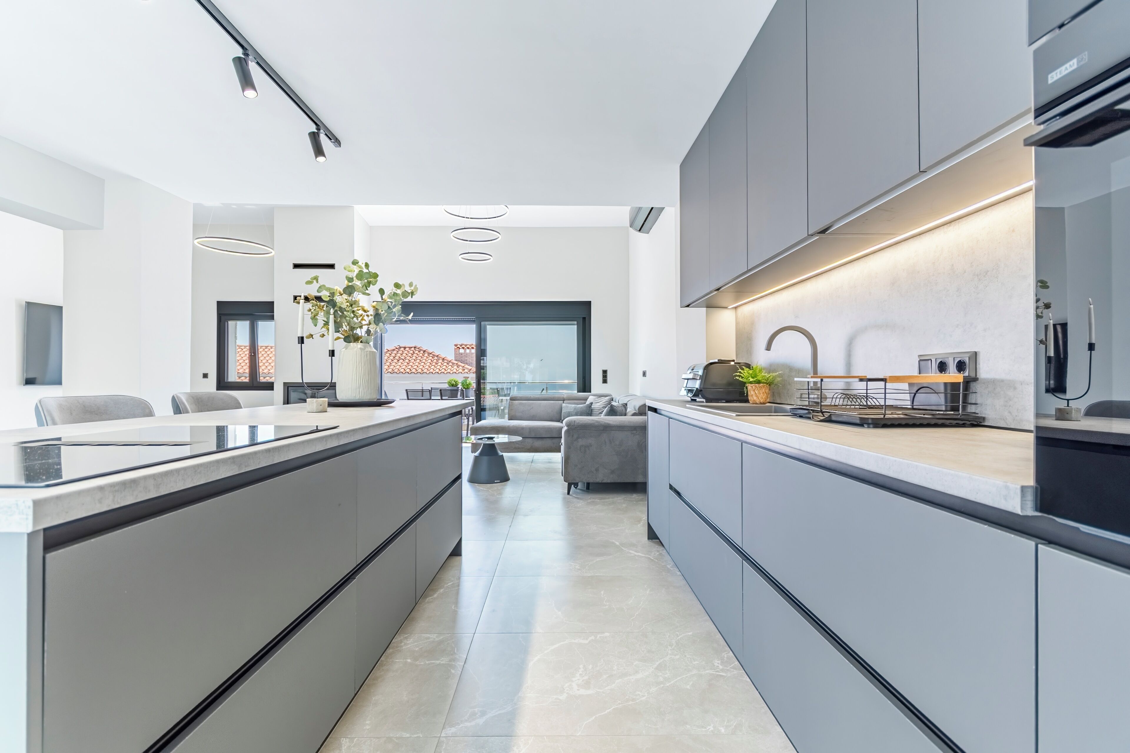 A modern kitchen with a central island, built-in appliances, and a dining area with a sofa and coffee table.