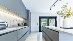 Une cuisine moderne équipée d’un four encastré, d’un évier et d’un plan de travail.