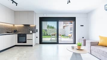 A modern kitchen with integrated appliances, a dining area with a round table, and a sliding glass door leading to an outdoor patio.