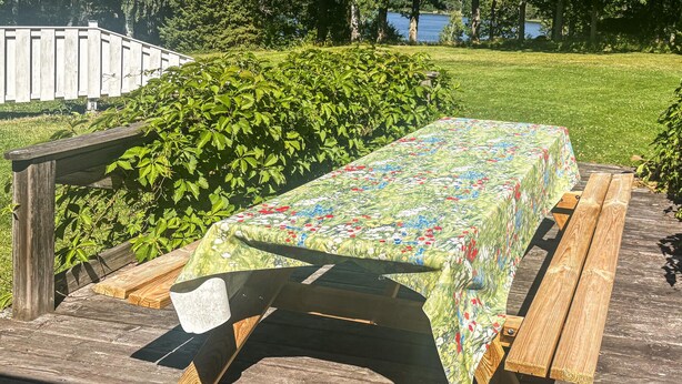 A picnic table with a floral tablecloth on a wooden deck. - 3 bedroom stunning home in Linköping (Linköping)