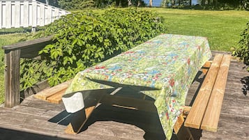 Una mesa de picnic con mantel floreado en una terraza de madera.