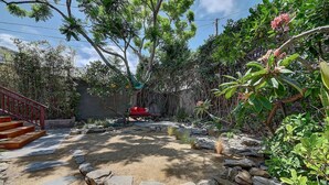 A garden with a stone pathway, a red bench, and a variety of plants. - Moden Craftsman • Pet Friendly • Sleeps 6 (Long Beach)