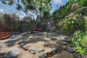 A garden with a stone pathway, a red bench, and a variety of plants. - Moden Craftsman • Pet Friendly • Sleeps 6 (Long Beach)