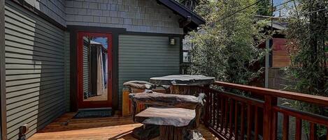 A wooden deck with a stone bench and a red door.