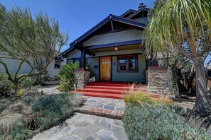 A two-story house with a stone foundation, a red front porch, and a blue exterior. - Moden Craftsman • Pet Friendly • Sleeps 6 (Long Beach)