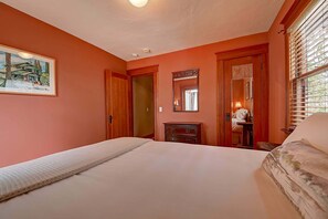 A bedroom with a bed, a dresser, a mirror, and a door leading to another room. - Moden Craftsman • Pet Friendly • Sleeps 6 (Long Beach)