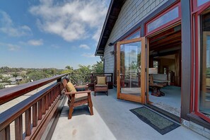 Un balcon doté de meubles en bois et d’une porte vitrée donnant sur un espace intérieur.