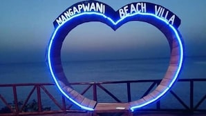 Et hjerteformet skilt med teksten 'Mangapwani Beach Villa', foran et hav.