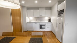 A modern kitchen with white cabinets, a built-in oven, and a refrigerator. - Ruka Ski Chalets (60m²) with balcony and WiFi (Kuusamo)