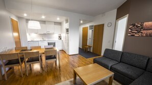 A modern living room with a sofa and a dining area with a table and chairs. - Ruka Ski Chalets (60m²) with balcony and WiFi (Kuusamo)