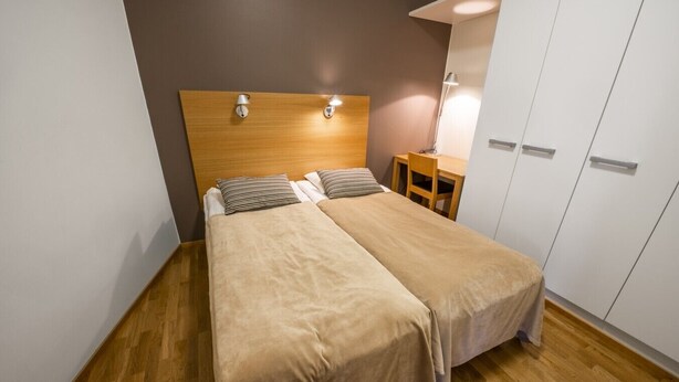 A double bed with a wooden headboard, a bedside table with a lamp, and a wardrobe with sliding doors. - Ruka Ski Chalets (60m²) with balcony and WiFi (Kuusamo)