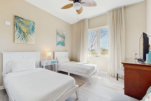 Ein Hotelzimmer mit zwei Betten, einem Schreibtisch, einem Fernseher und Kunstwerken an den Wänden.