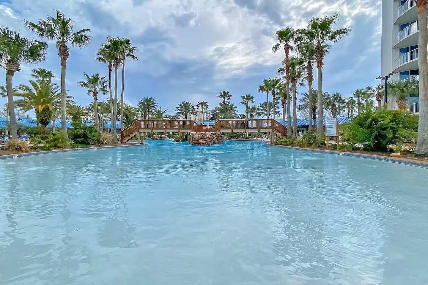 Una piscina con palme e un ponte di legno.