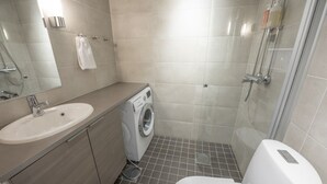 Un baño moderno con lavabo, lavadora, inodoro y ducha.