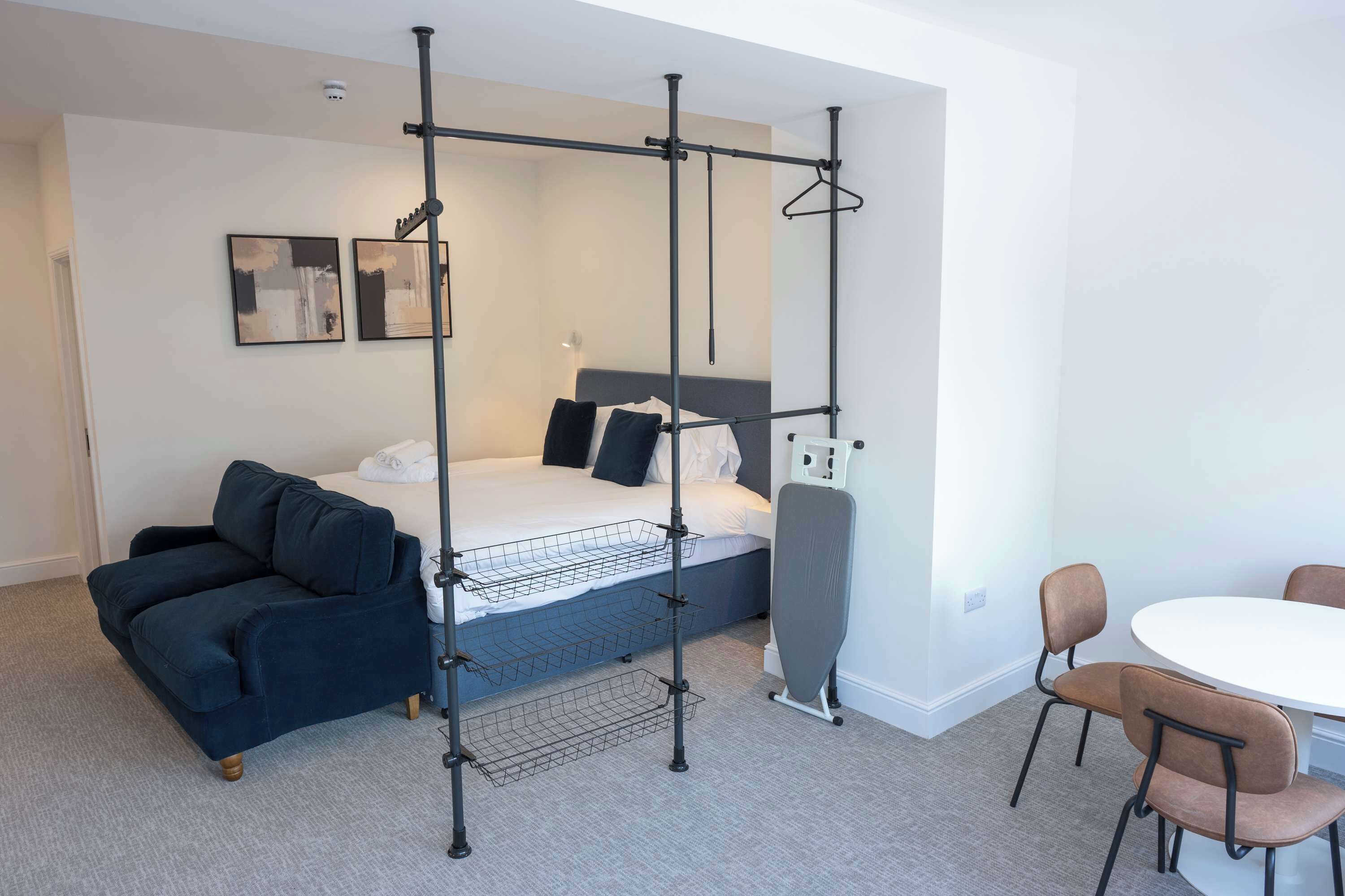 A modern hotel room with a bed, a sofa, a desk, and a chair.