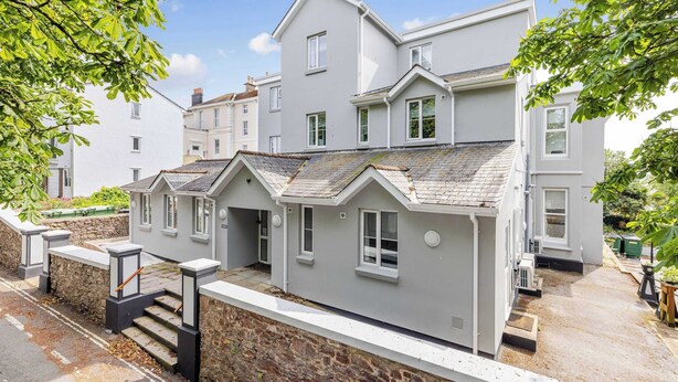 A multi-story residential building with a stone foundation, multiple windows, and a flat roof. - The Maycliffe - Studio near Torquay Harbour (Torquay)