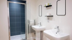 A bathroom with a glass shower enclosure, two sinks, and a towel rack. - The Maycliffe - Studio near Torquay Harbour (Torquay)